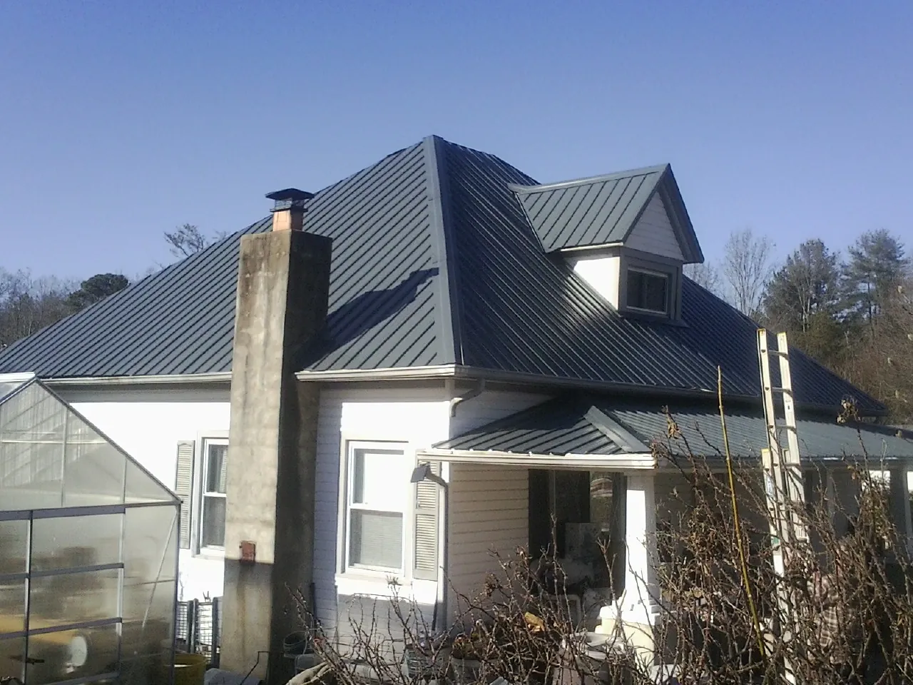 Dark blue standing seam metal roof on a white farmhouse with dormer — Slate & Tile Roof Repair by Roofing Brothers in Ridge Spring