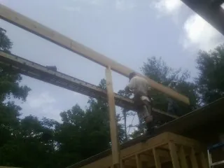 Carpenter setting a ridge beam over a new addition frame — Ice Dam Removal by Roofing Brothers in Ridge Spring
