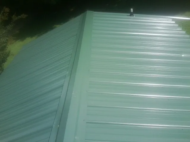 New green metal panels meeting at the ridge of a roof — Flat Roof Repair work by our crew in Ridge Spring