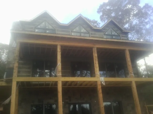 Dormers and porch framing on a large log home under construction — Roof Coating work by our crew in Ridge Spring