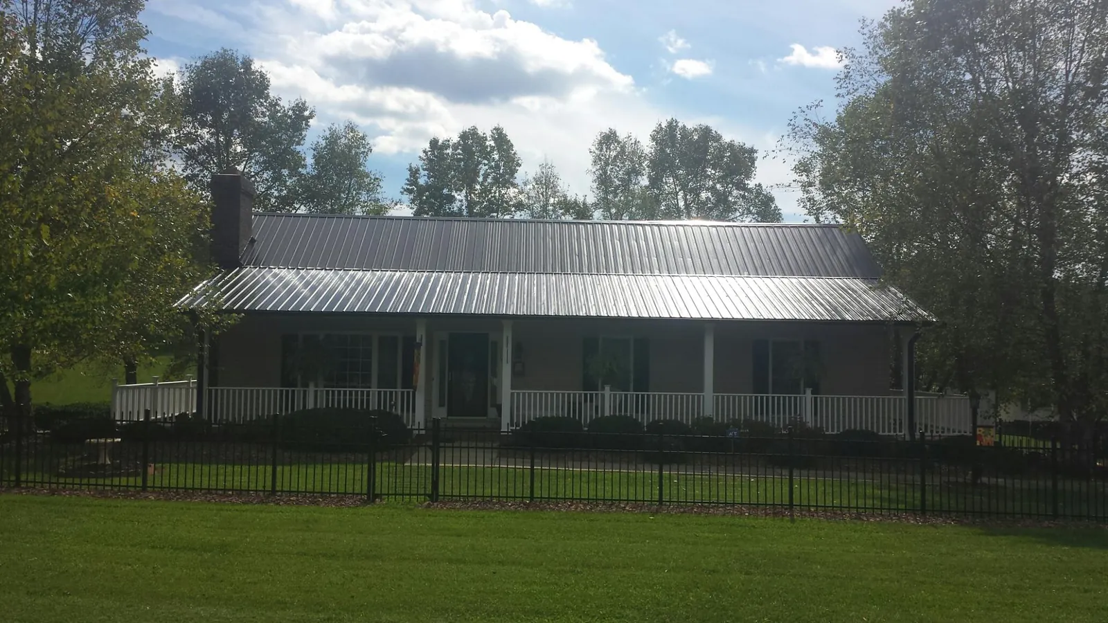 Gray metal roof on a brick ranch with a full width front porch — Gutter Guard Installation work by our crew in Ridge Spring