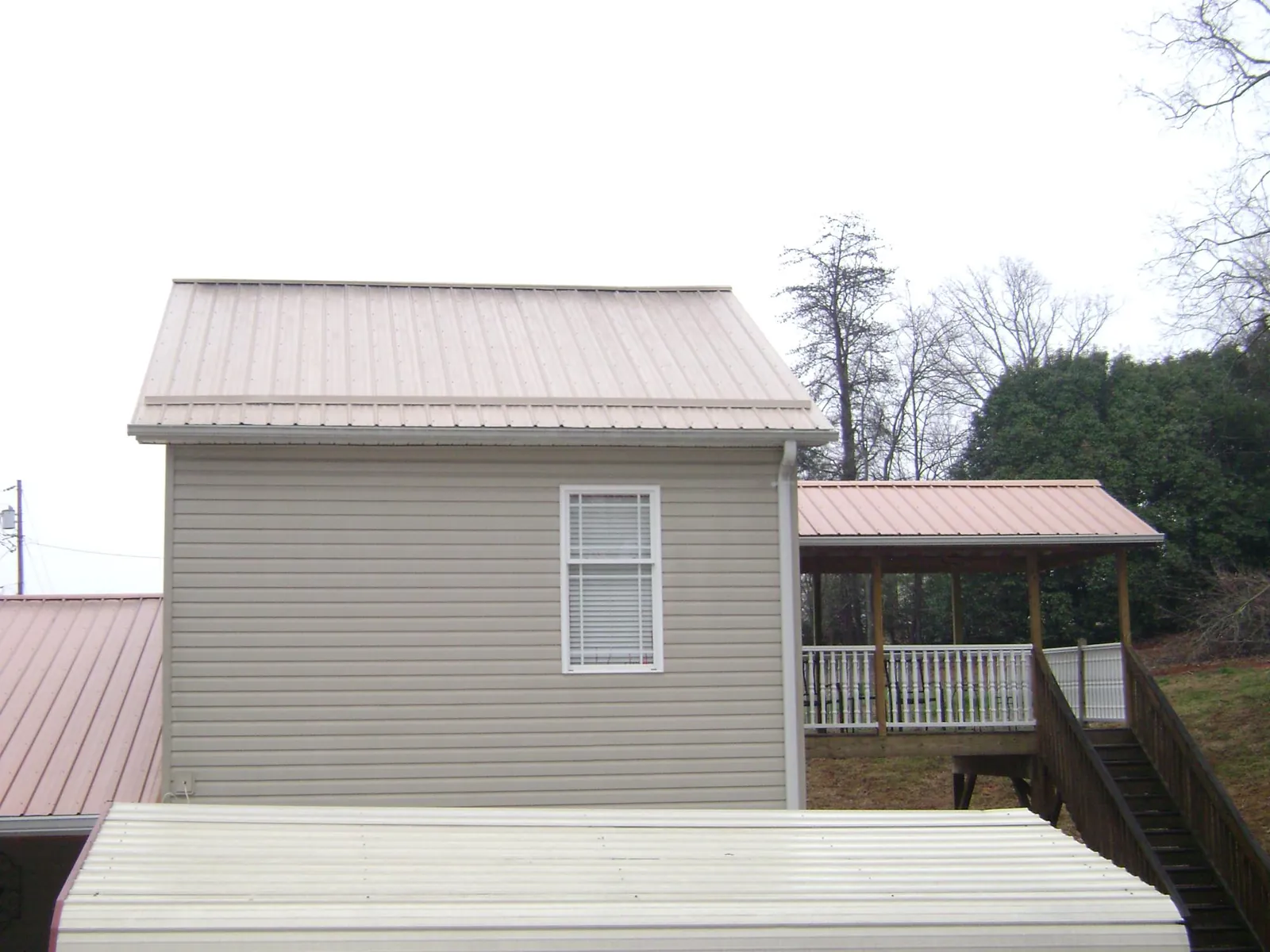 Tan metal roofs on a two story addition and attached porch, from a Roof Replacement job in Ridge Spring